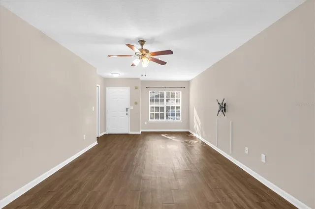 a view of an empty room with a window and wooden floor