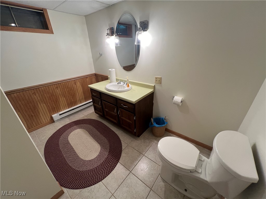 86422 North Bay Road Scio, OH 43988 - Photo 25 of 47 Bathroom with toilet, wooden walls, tile patterned floors, vanity, and a baseboard heating unit