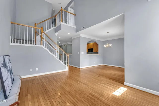 an empty room with wooden floor fireplace and windows
