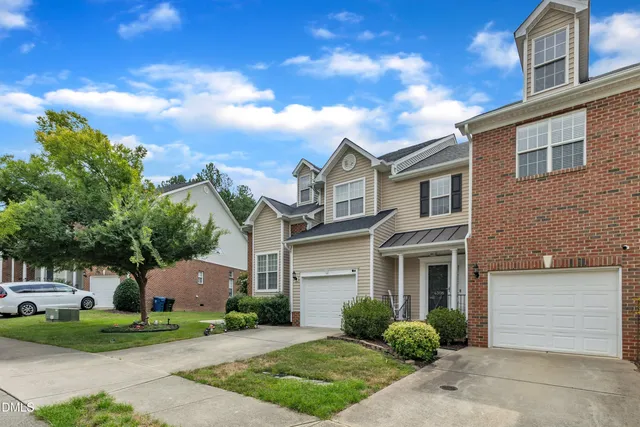 a front view of a house with a garden and a car