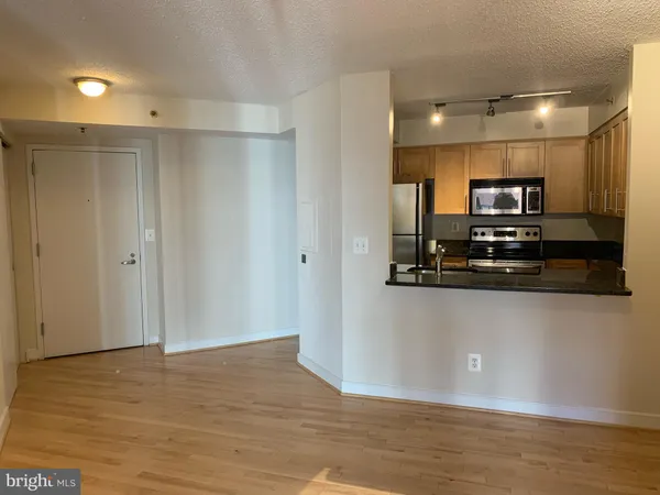 a view of kitchen with stainless steel appliances granite countertop a refrigerator and a microwave