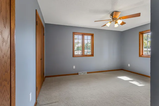 an empty room with windows and chandelier fan