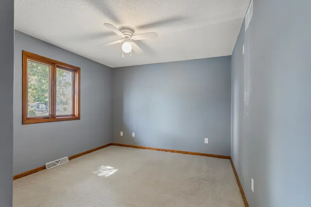 an empty room with windows and fan