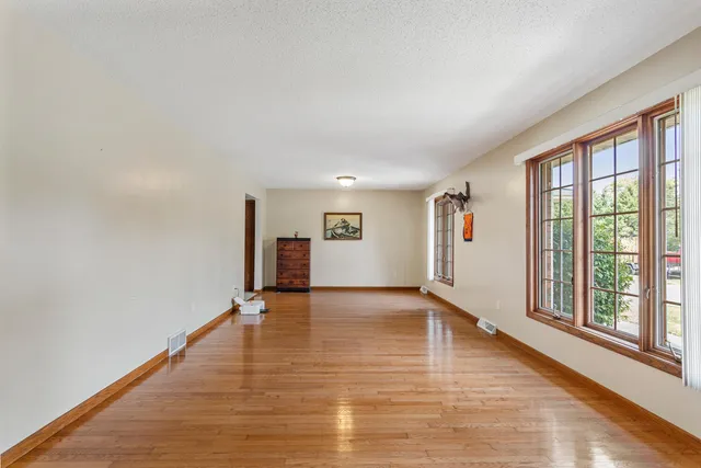 a view of an empty room with window and wooden floor