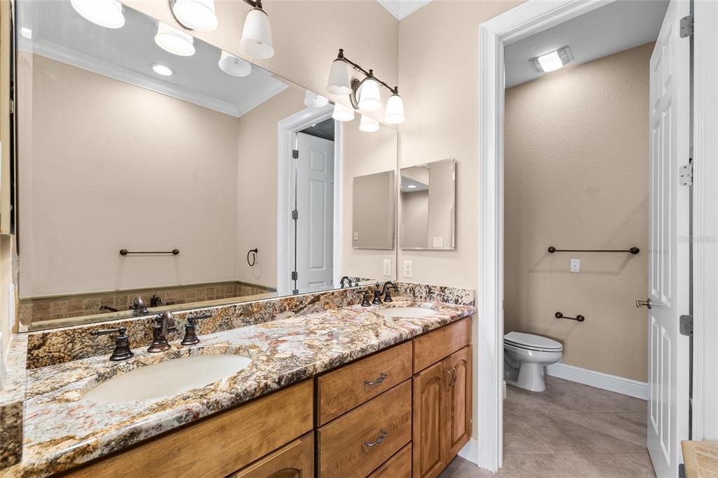 6002 Printery Street, Unit 105 Tampa, FL 33616 - Photo 30 of 64 a bathroom with a granite countertop double vanity sink mirror and toilet