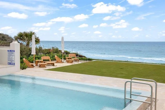a view of a swimming pool with a lawn chairs under an umbrella
