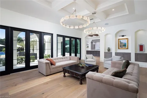 a living room with furniture chandelier and large windows