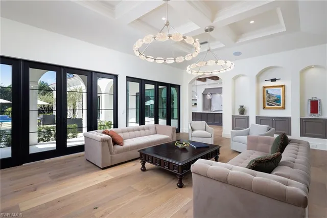 a living room with furniture chandelier and large windows