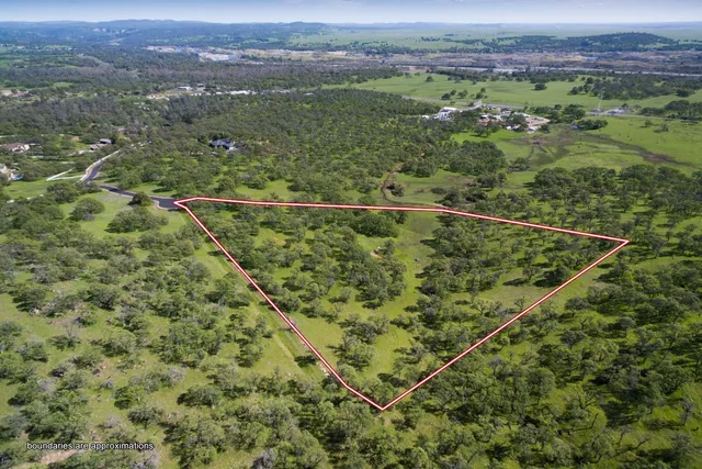 an aerial view of a residential houses with outdoor space and trees