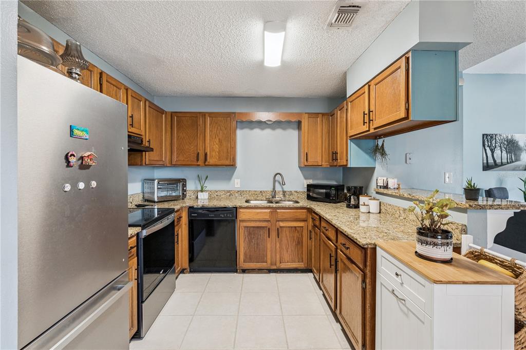 518 Torrey Avenue Altamonte Springs, FL 32714 - Photo 9 of 27 a kitchen with stainless steel appliances granite countertop a stove top oven a sink dishwasher a refrigerator and cabinets with wooden floor