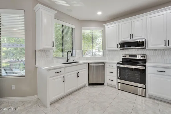 a kitchen with granite countertop white cabinets and stainless steel appliances