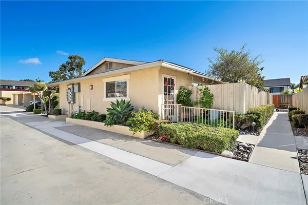 a view of a white house with a small yard and plants
