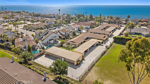 an aerial view of a city with lots of residential buildings and ocean view in back
