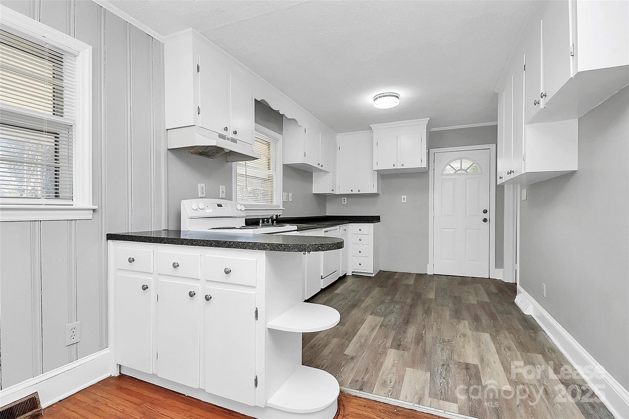 4919 Raymond Place Charlotte, NC 28205 - Photo 18 of 31 a kitchen with a sink dishwasher a refrigerator and white cabinets with wooden floor