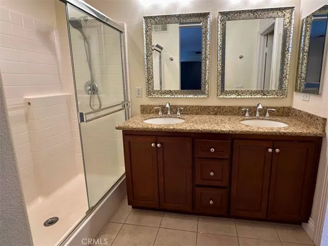 a bathroom with a granite countertop sink a mirror and a shower