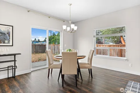 a dining room with wooden floor a chandelier a wooden table and chairs