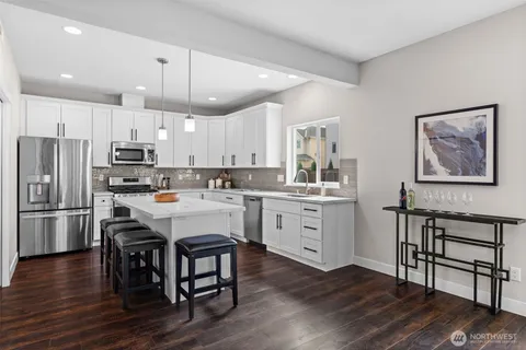 a kitchen with a refrigerator a white stove top oven cabinets and a dining table