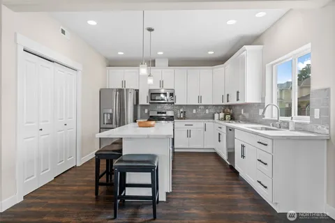 a kitchen with stainless steel appliances granite countertop a white cabinets wooden floor and a sink