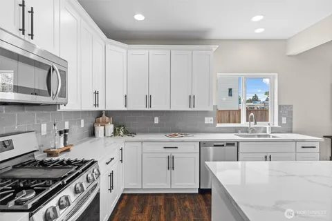 a kitchen with stainless steel appliances granite countertop a stove a sink dishwasher and cabinets with wooden floor