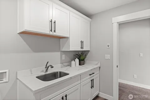 a kitchen with white cabinets a sink and dishwasher with wooden floor