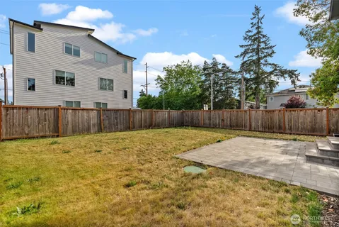 a view of a backyard with large tree and wooden fence