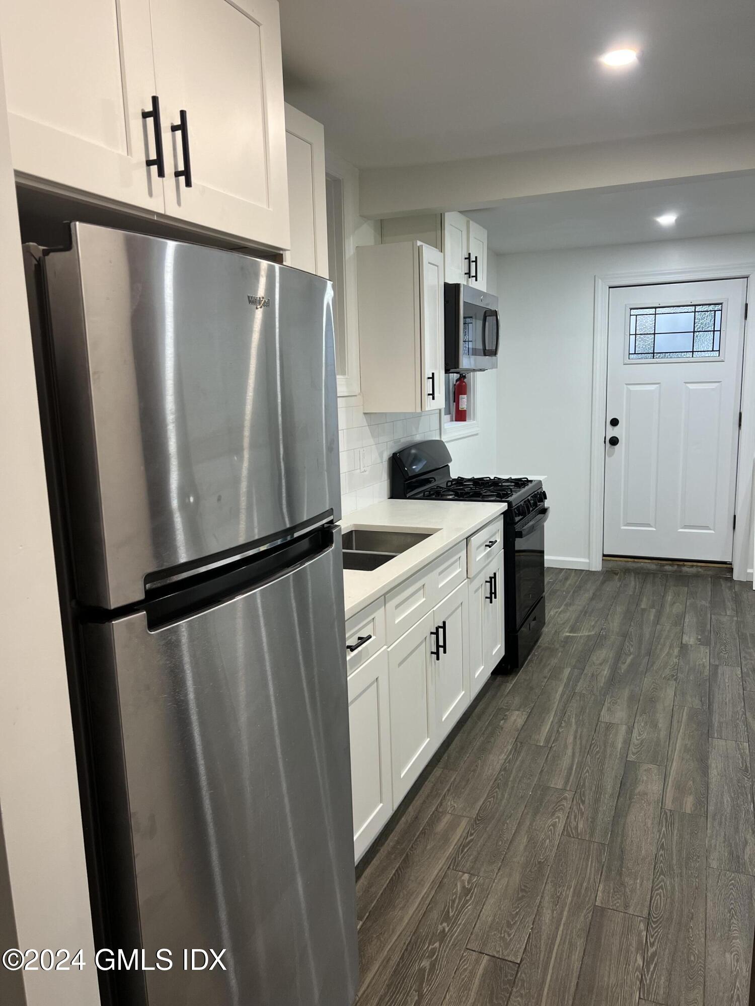 119 North Water Street, Unit 1 Greenwich, CT 06830 - Photo 4 of 11 a kitchen with stainless steel appliances a refrigerator and wooden floor