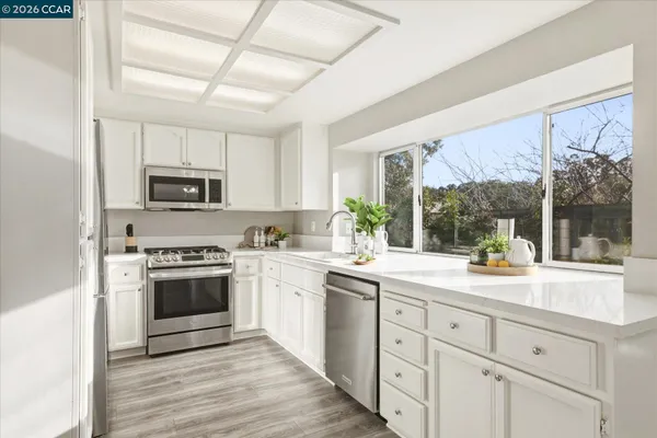 a kitchen with kitchen island granite countertop white cabinets white stainless steel appliances and a sink