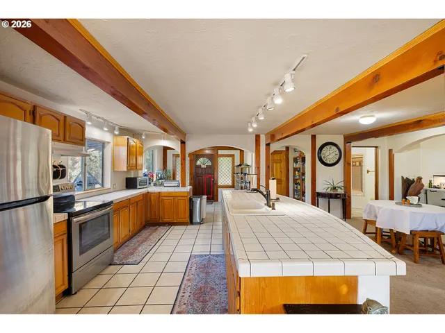 a kitchen with stainless steel appliances kitchen island granite countertop a refrigerator a stove and a sink with cabinets