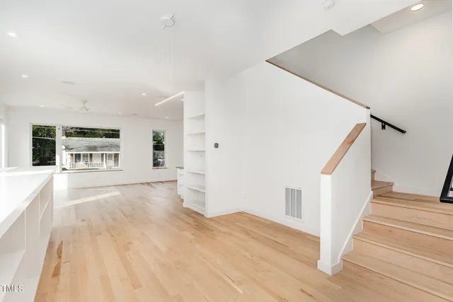 a view of an empty room with wooden floor and stairs