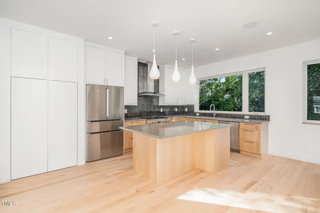 a kitchen with stainless steel appliances granite countertop a refrigerator a sink a stove and a refrigerator