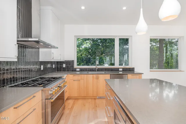 a kitchen with stainless steel appliances a large window cabinets and a stove top oven