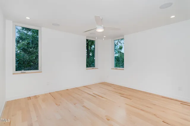 an empty room with wooden floor and windows