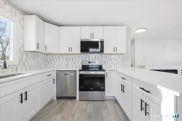 a kitchen with cabinets stainless steel appliances a sink and wooden floor