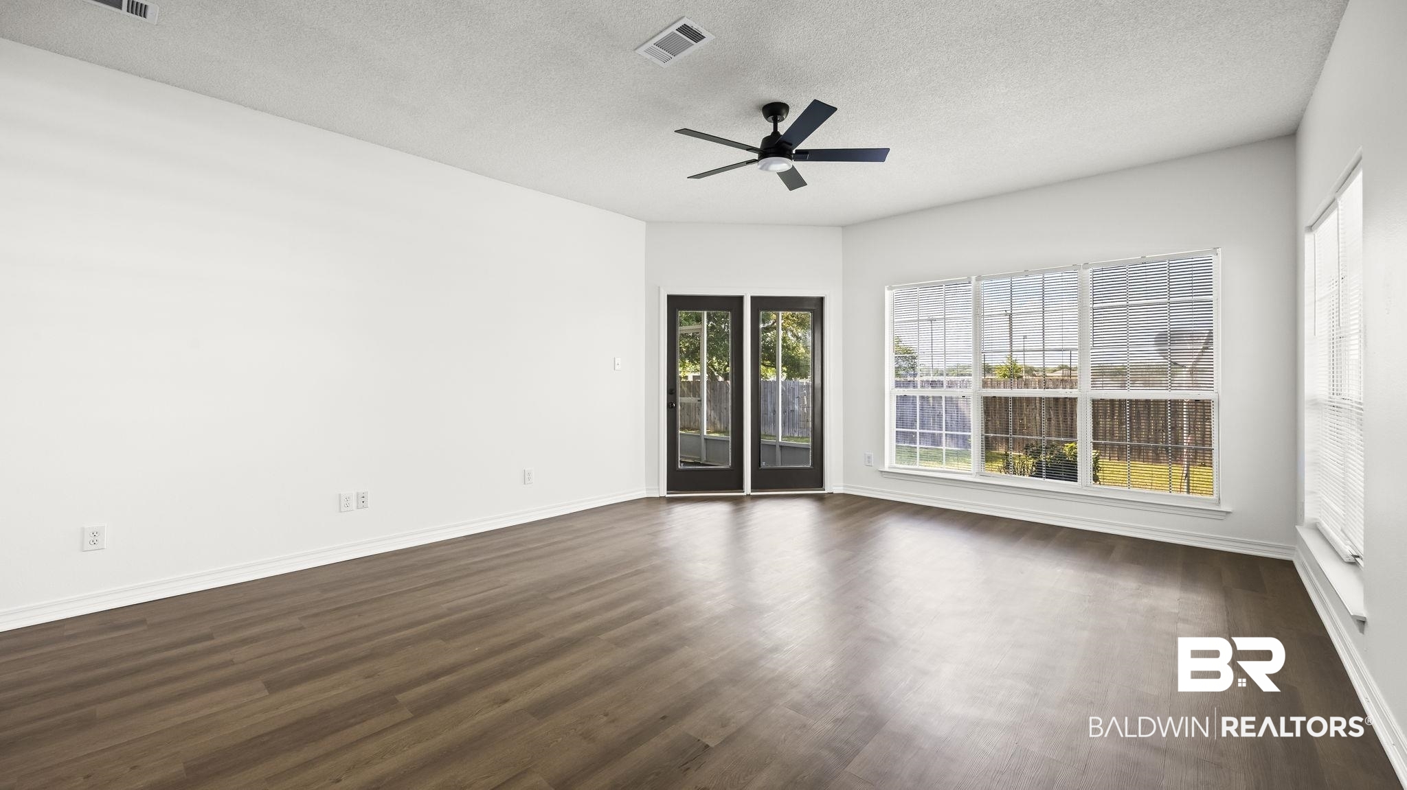 2651 South Juniper Street, Unit 705 Foley, AL 36535 - Photo 11 of 37 Spacious room featuring wood-finish flooring, crisp white walls, and a vaulted ceiling with a black ceiling fan