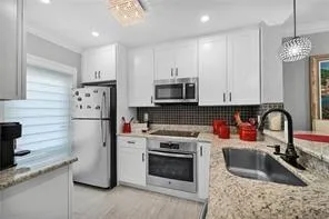 a kitchen with stainless steel appliances granite countertop a sink stove and refrigerator