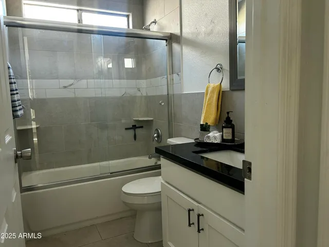 a bathroom with a granite countertop bathtub shower sink and toilet