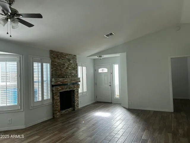 an empty room with wooden floor fireplace and windows