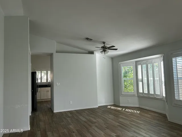 a view of an empty room with window and wooden floor