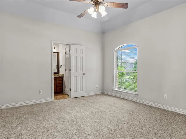 an empty room with chandelier fan and windows