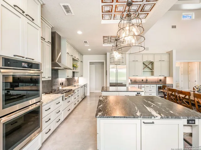 a kitchen with granite countertop a sink cabinets stainless steel appliances and a window