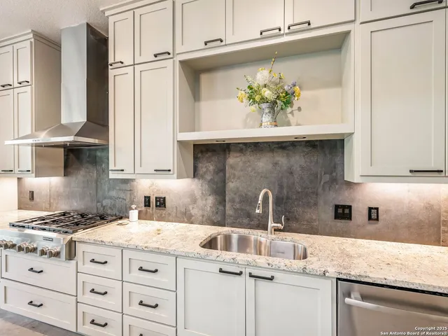 a large white kitchen with a sink stainless steel appliances and cabinets