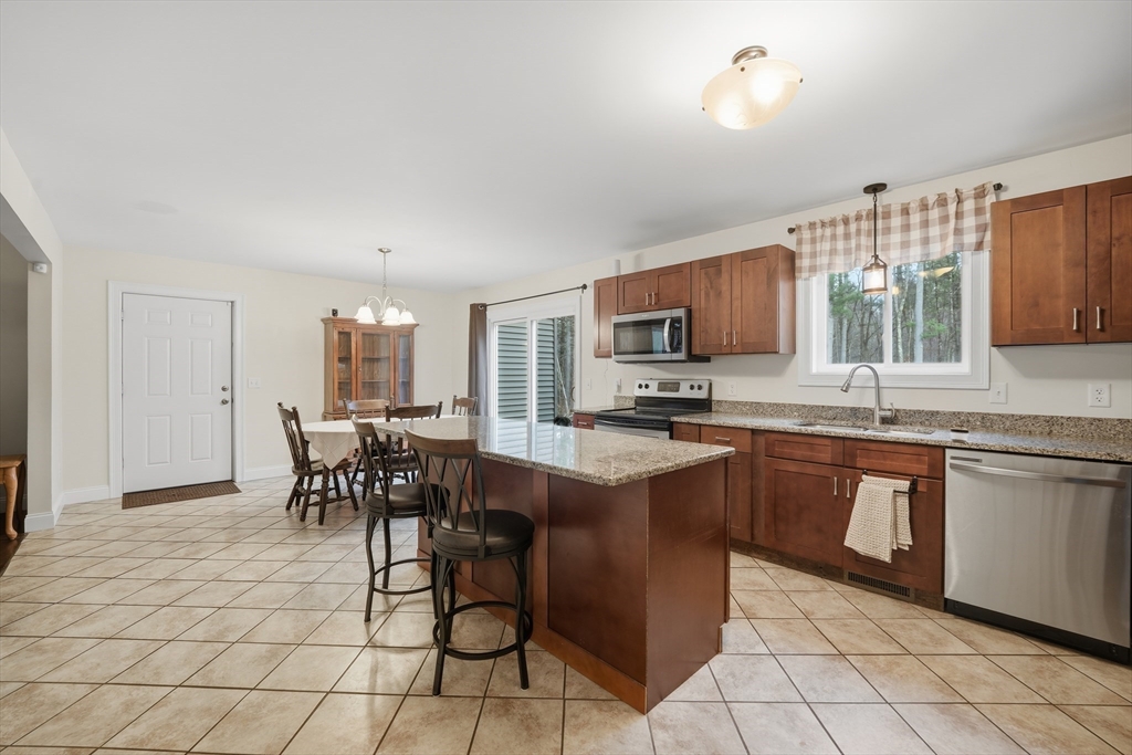 209 Osborne Road Ware, MA 01082 - Photo 11 of 32 a kitchen with stainless steel appliances granite countertop a stove top oven a sink a dining table and chairs