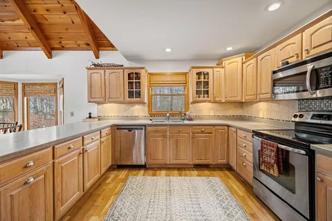 a kitchen with stainless steel appliances granite countertop a refrigerator a stove and a sink with wooden floor