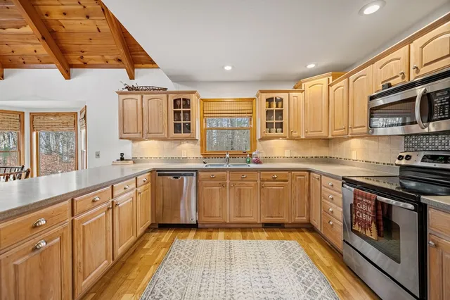a kitchen with stainless steel appliances granite countertop a refrigerator a stove and a sink with wooden floor