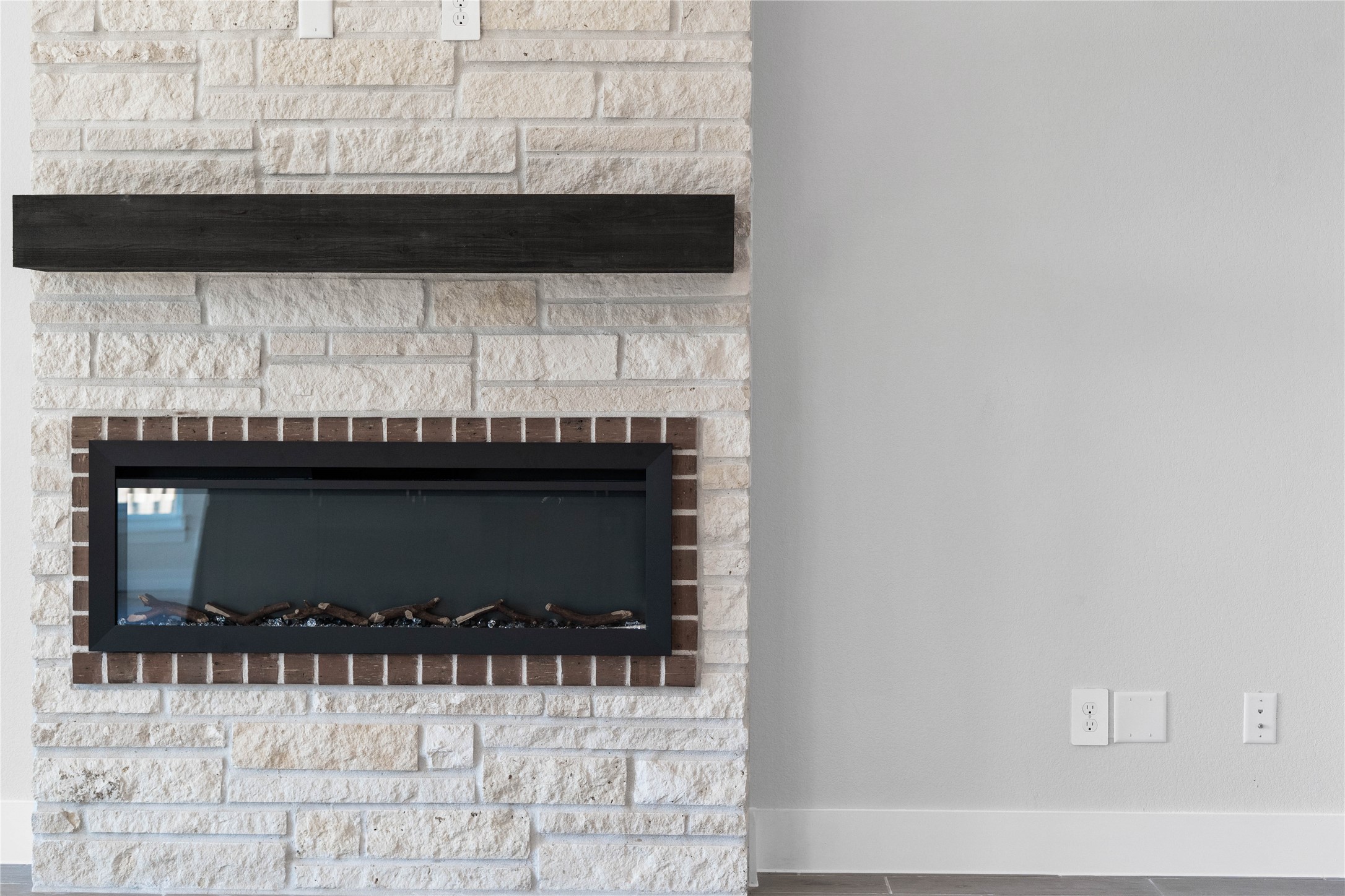 2114 Rowl Street Montgomery, TX 77316 - Photo 20 of 50 The sleek linear gas insert is framed by a decorative brick border, creating a unique architectural detail. The look is completed with a dark espresso wood-beam mantel, providing a bold contrast against the natural white stone.