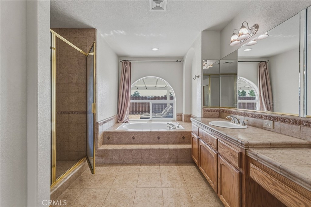 19501 Kinai Road Apple Valley, CA 92307 - Photo 28 of 49 a spacious bathroom with a granite countertop sink a mirror and a bathtub