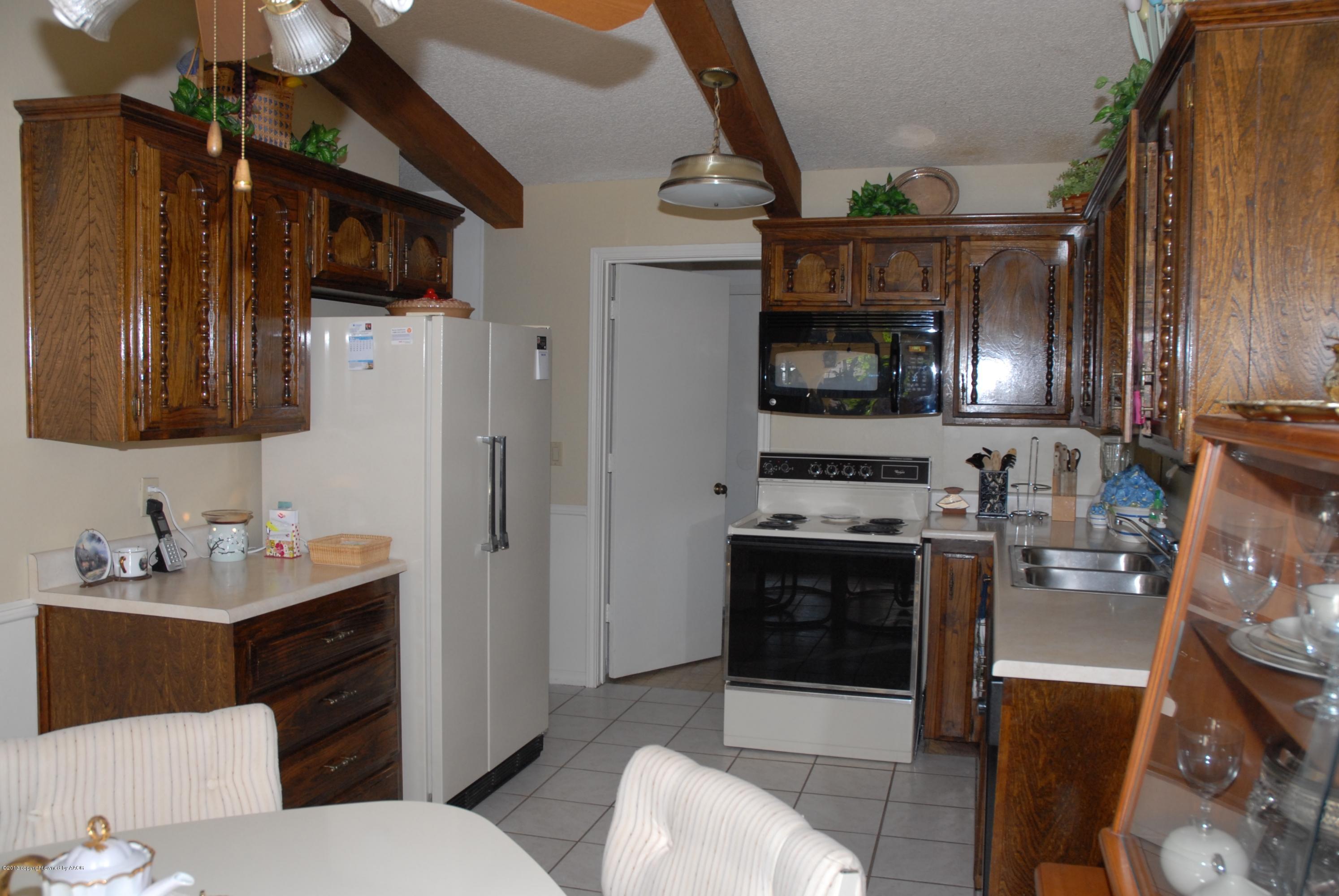8207 Goodnight Trail Amarillo, TX 79110 - Photo 7 of 16 a kitchen with stainless steel appliances a stove a sink dishwasher and a refrigerator with wooden cabinets