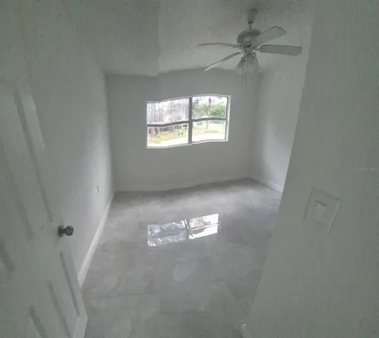 an empty room with windows and fan