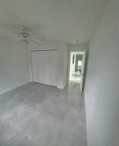 an empty room with chandelier fan and windows