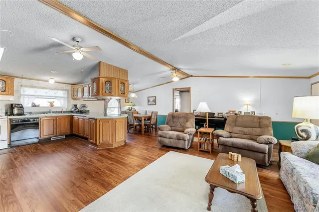 a living room with furniture kitchen view and a wooden floor